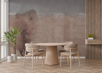 Round wooden dining table set against a watercolor light beige wall mural.