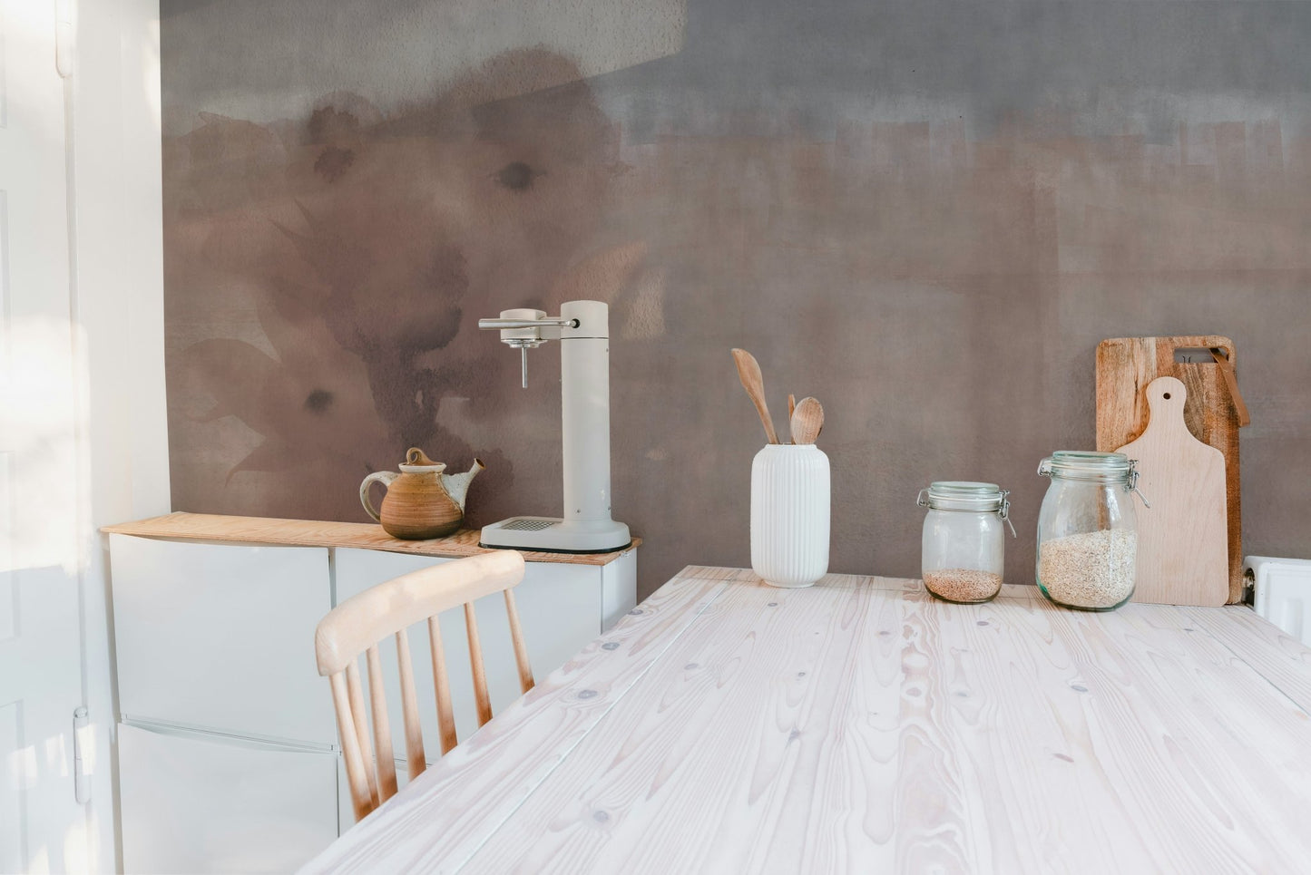 Minimalist kitchen featuring earthy beige wall mural and wooden dining table.