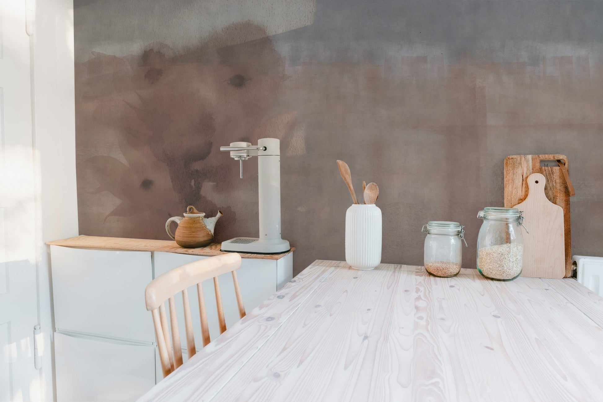 Minimalist kitchen featuring earthy beige wall mural and wooden dining table.