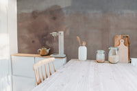 Minimalist kitchen featuring earthy beige wall mural and wooden dining table.