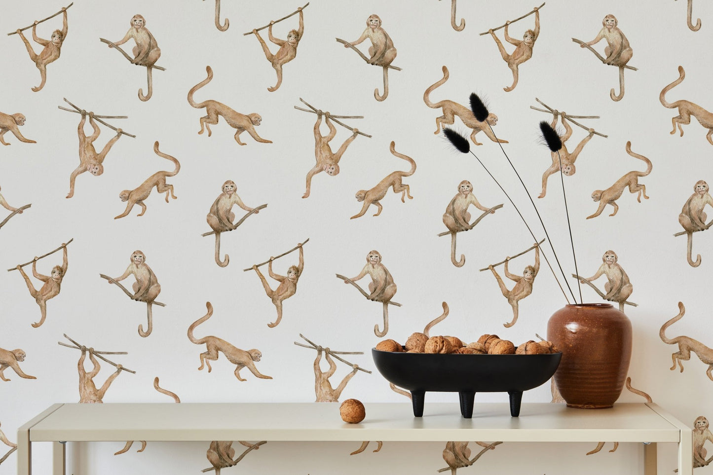 Cream and brown monkey print wallpaper behind a dining table with ceramic decor.