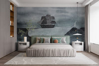 Nautical theme wall mural with a whale and ship above a grey upholstered bed.