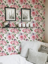 Pink floral wallpaper in a living room with grey pillows and framed art.