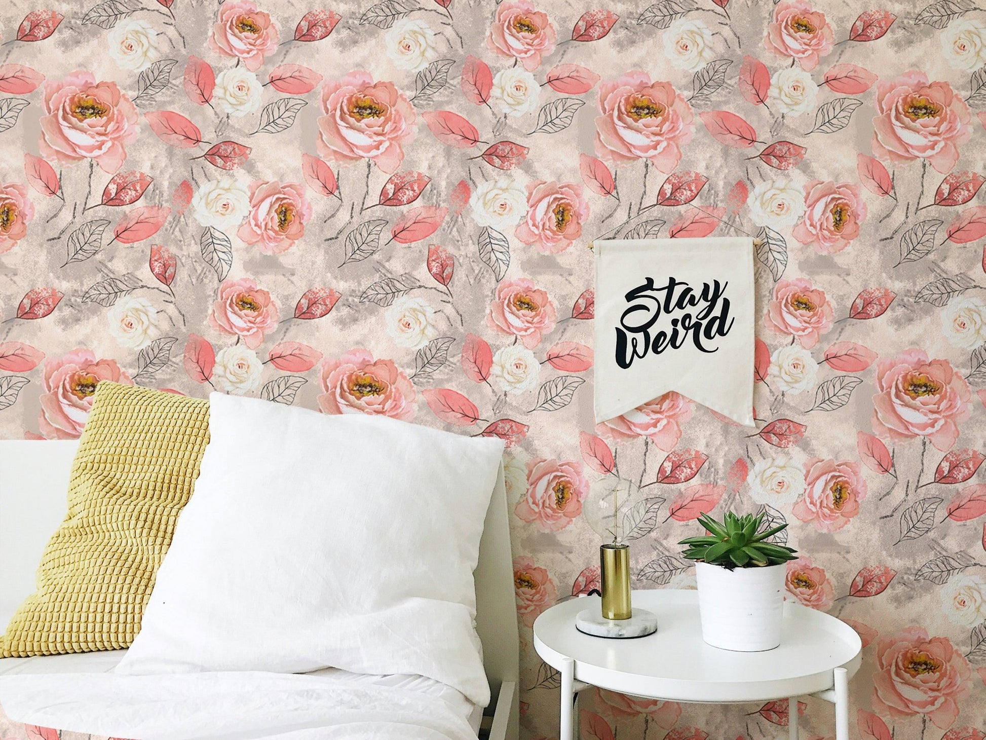 Watercolor pink roses flower wallpaper in a bedroom behind a white bed and side table.