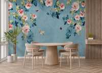 Round wooden dining table set against a teal watercolor rose wall mural.