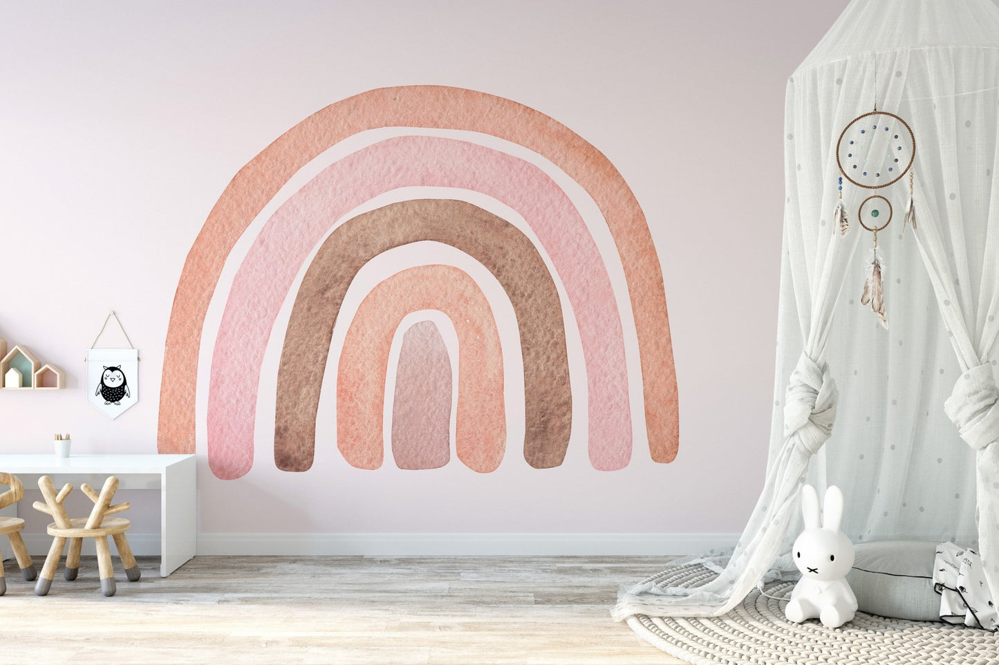 Minimalist playroom wall mural with pink rainbow and white play table.