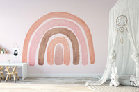 Minimalist playroom wall mural with pink rainbow and white play table.