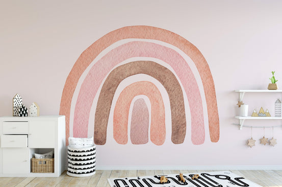 Watercolor rainbow mural on pink wall in kids play area with white storage.