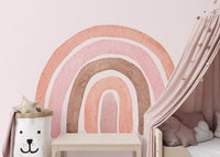 Soft pink watercolor rainbow wall mural in a child's sleep space with canopy.