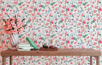 Multi-colored floral wallpaper in a study with a small wooden desk and vase.