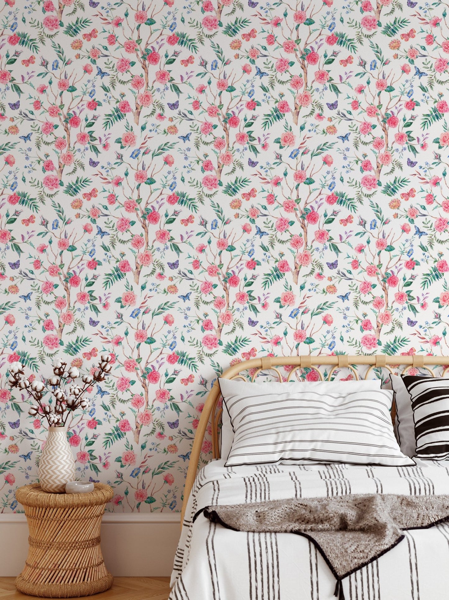 Watercolor rose wallpaper behind a bed with neutral linens and wood side table.