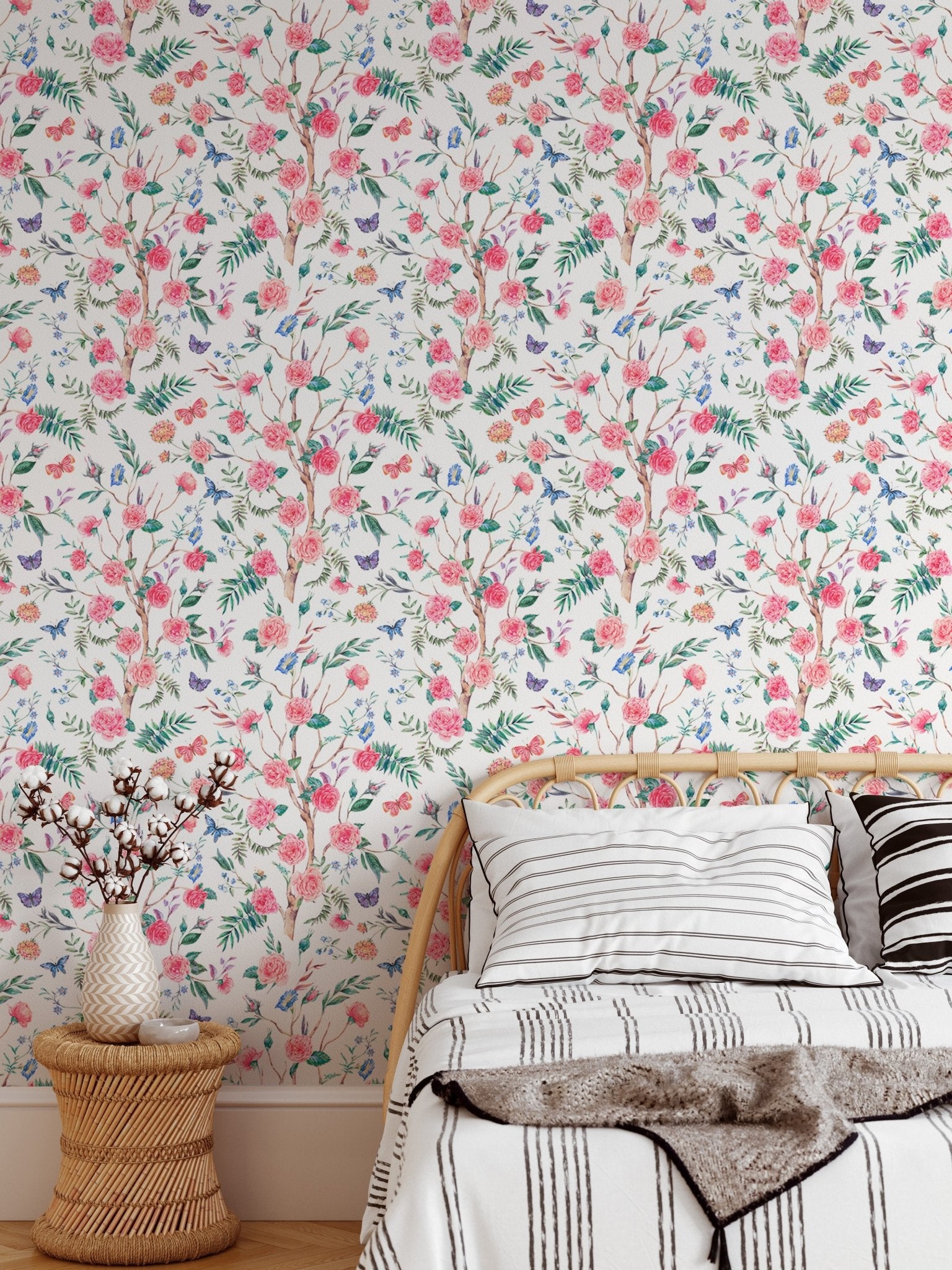 Watercolor rose wallpaper behind a bed with neutral linens and wood side table.