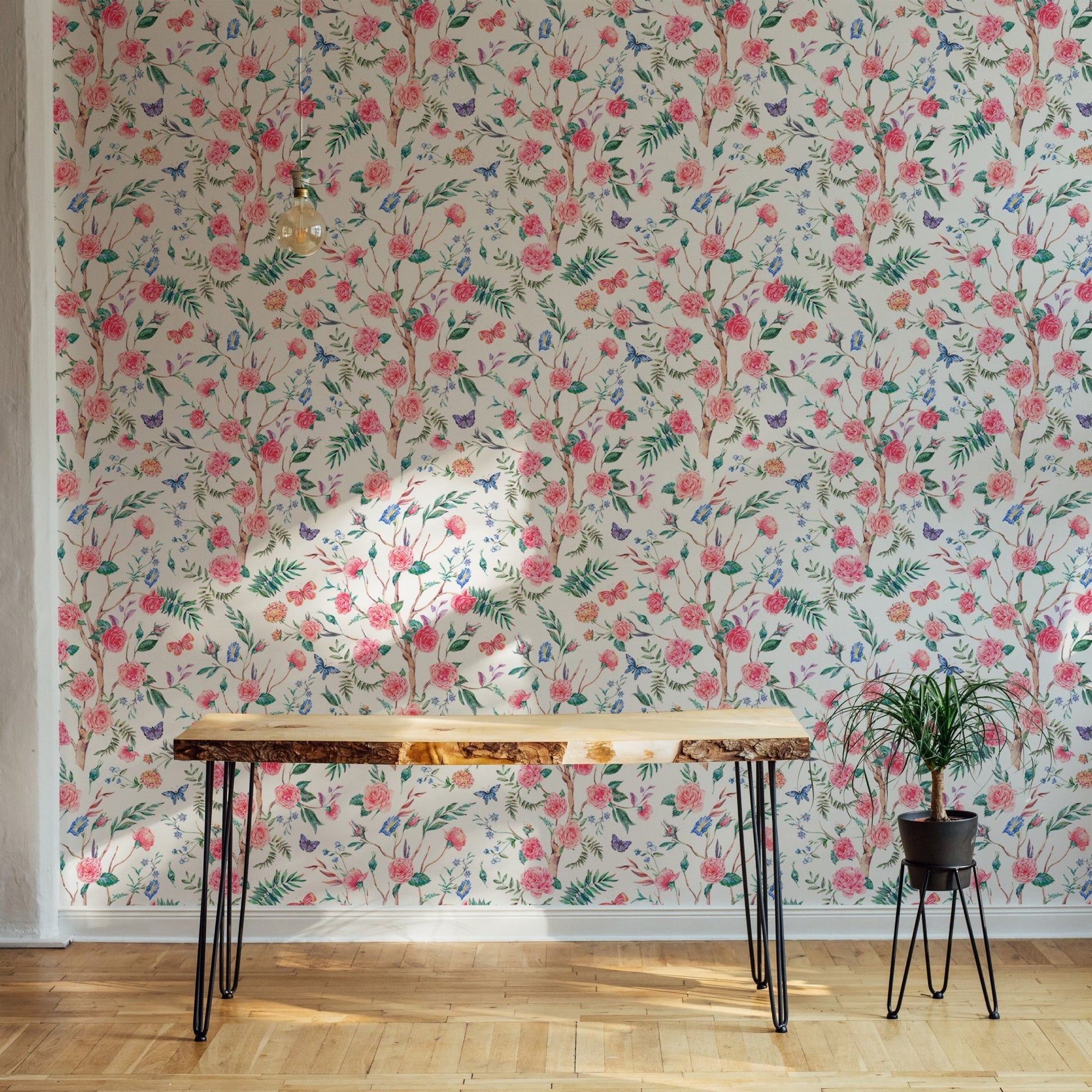 Pink floral wallpaper in a workspace with a wooden desk and potted plant.