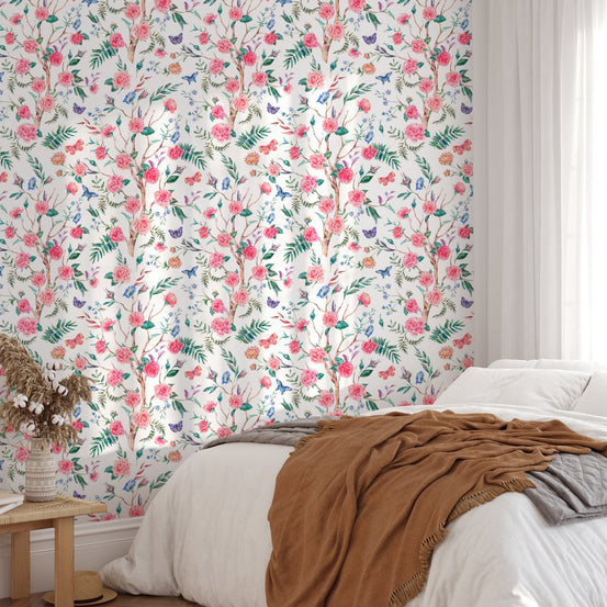 White floral wallpaper in a bedroom with white bed and small table.