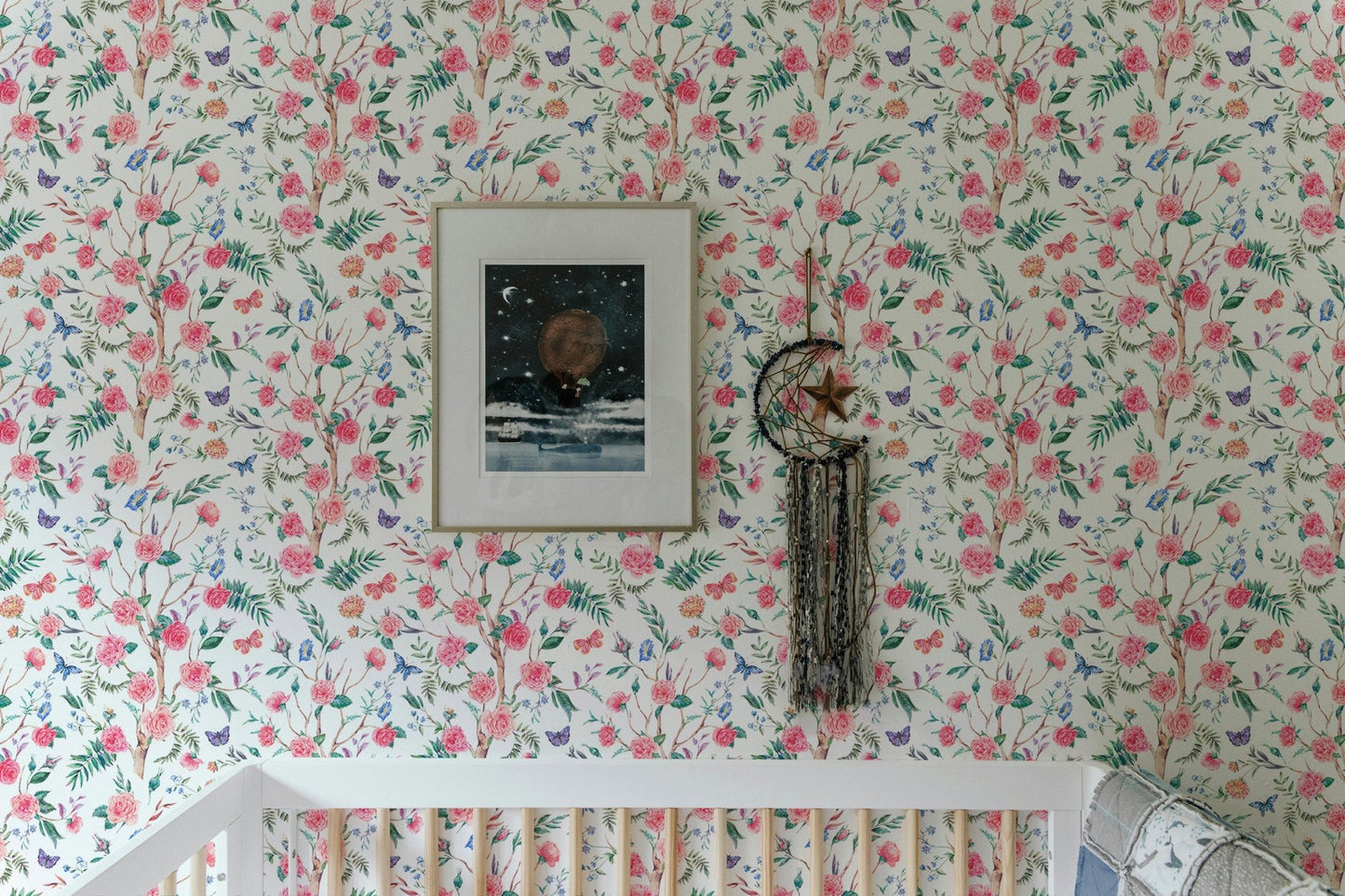 White floral wallpaper in a child's room above a white wooden crib.