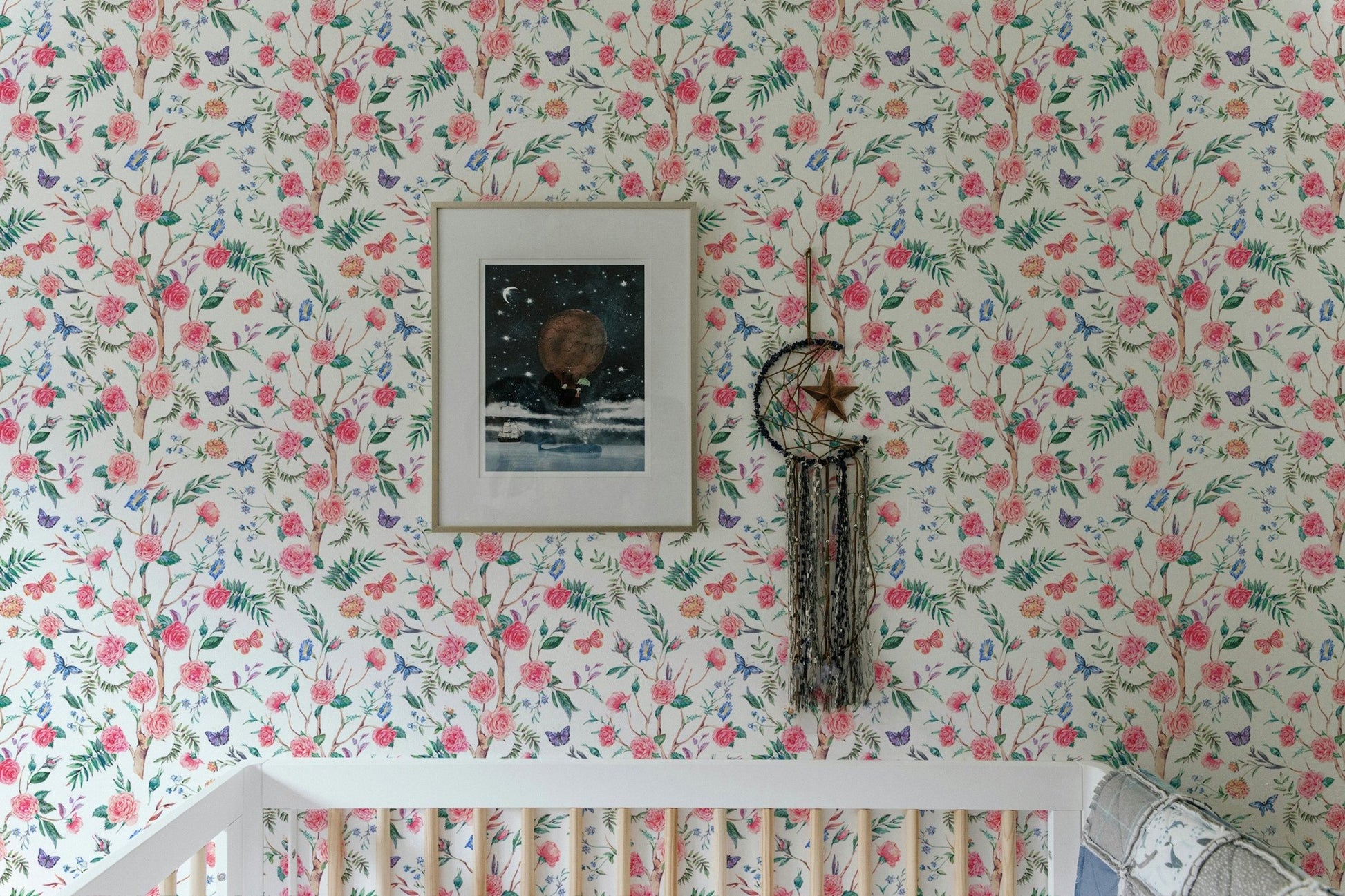 White floral wallpaper in a child's room above a white wooden crib.