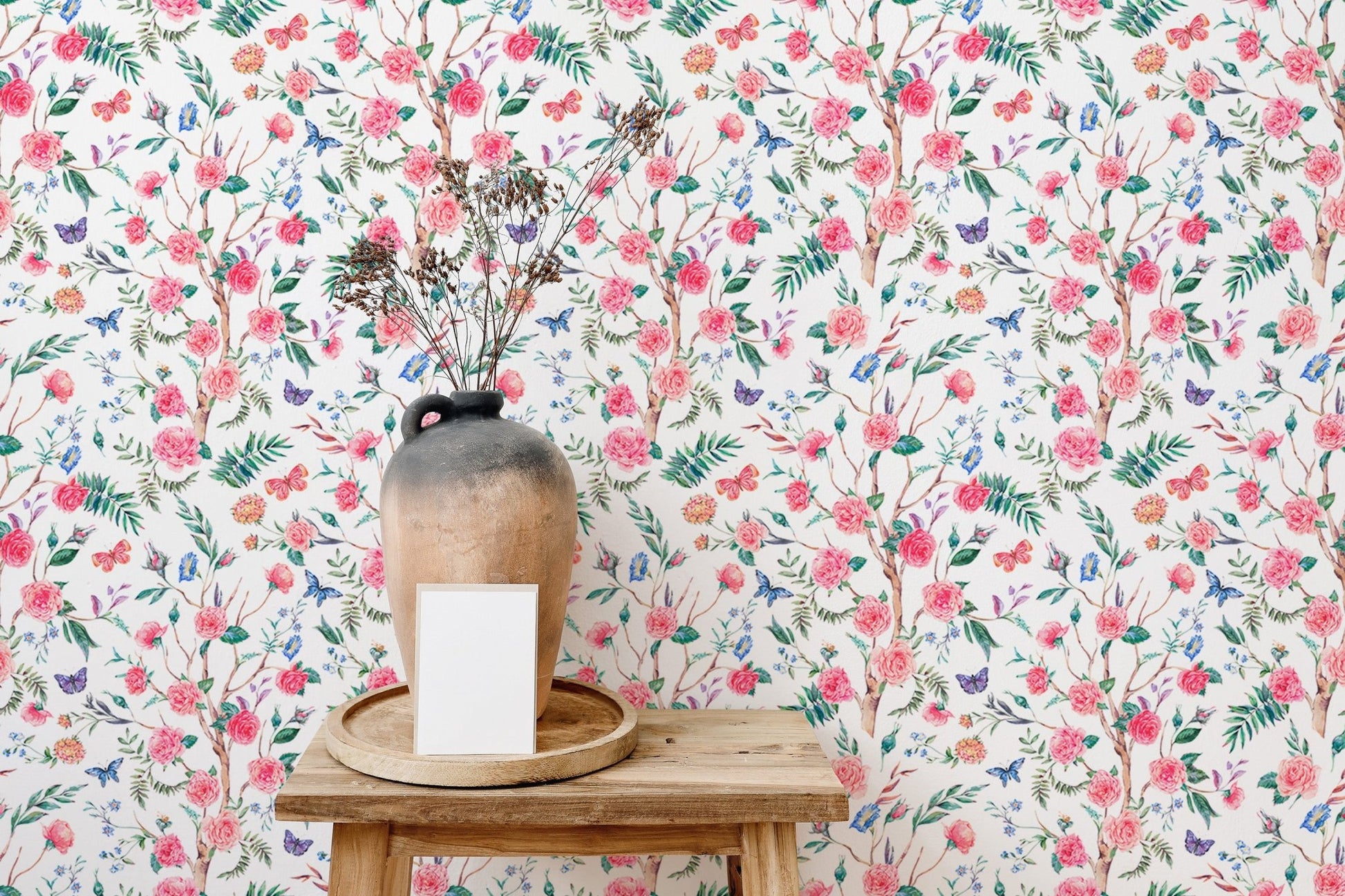 Blooming rose wallpaper behind a wooden stool with a ceramic vase.
