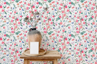 Blooming rose wallpaper behind a wooden stool with a ceramic vase.