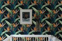 Dark botanical wallpaper featuring tropical leaves behind a bed.