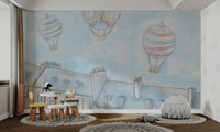 Muted pink and yellow striped balloon on light blue wall mural in nursery.