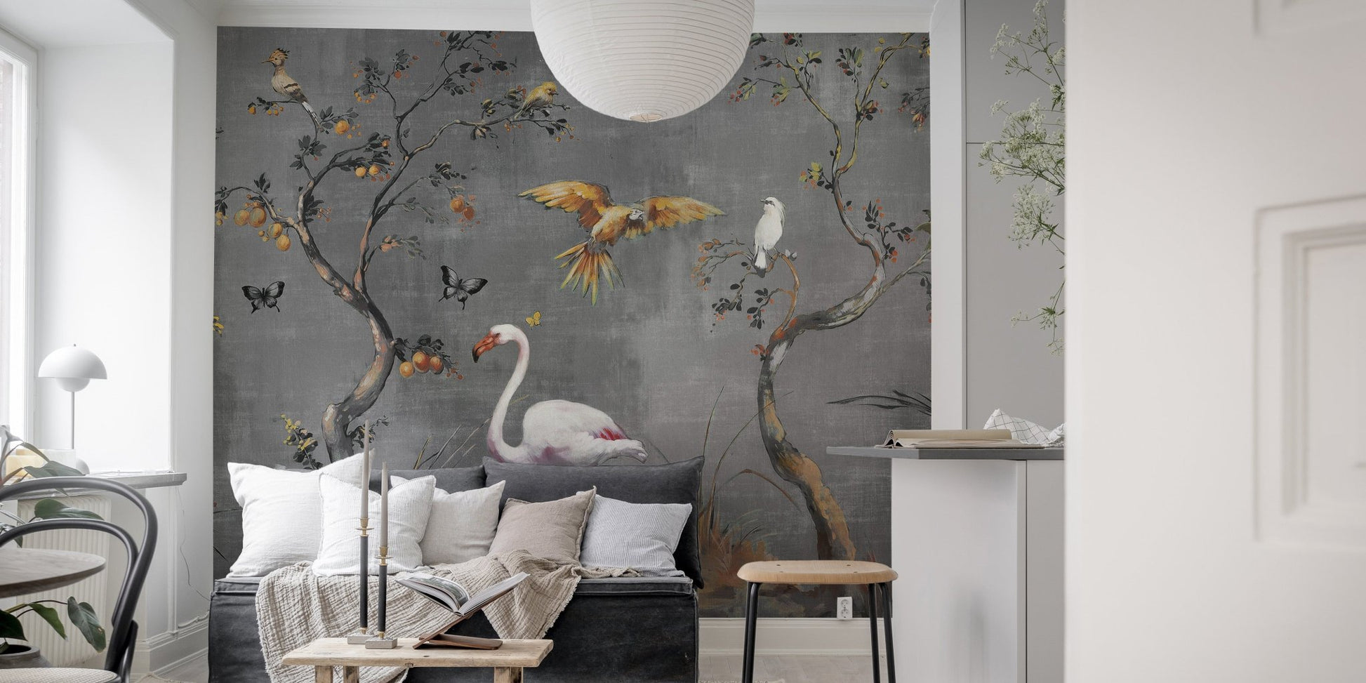 Grey fables wall mural featuring white flamingos and golden birds behind a grey sofa in living room.