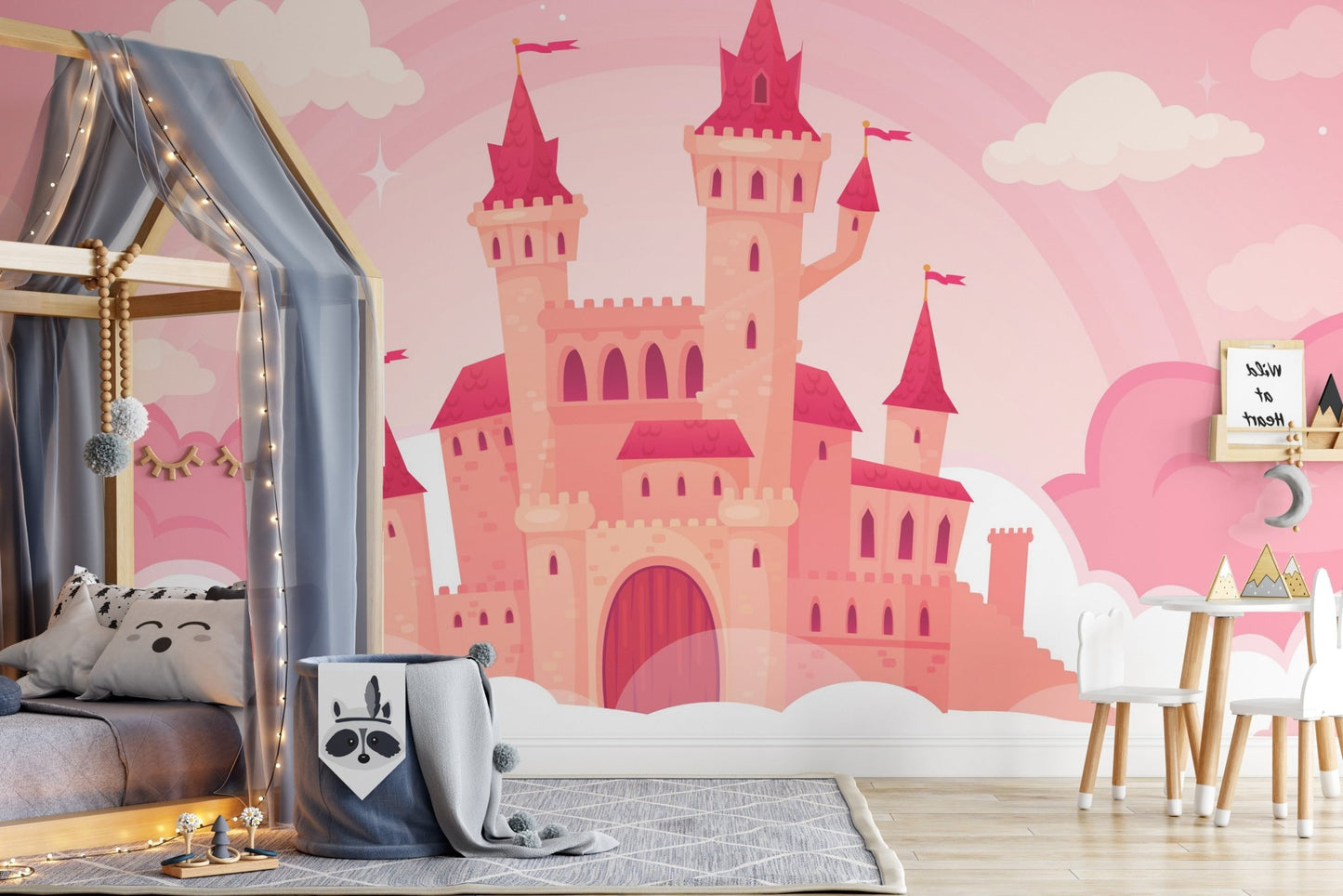 Pink castle wall mural behind a grey bed frame and wooden play structures.