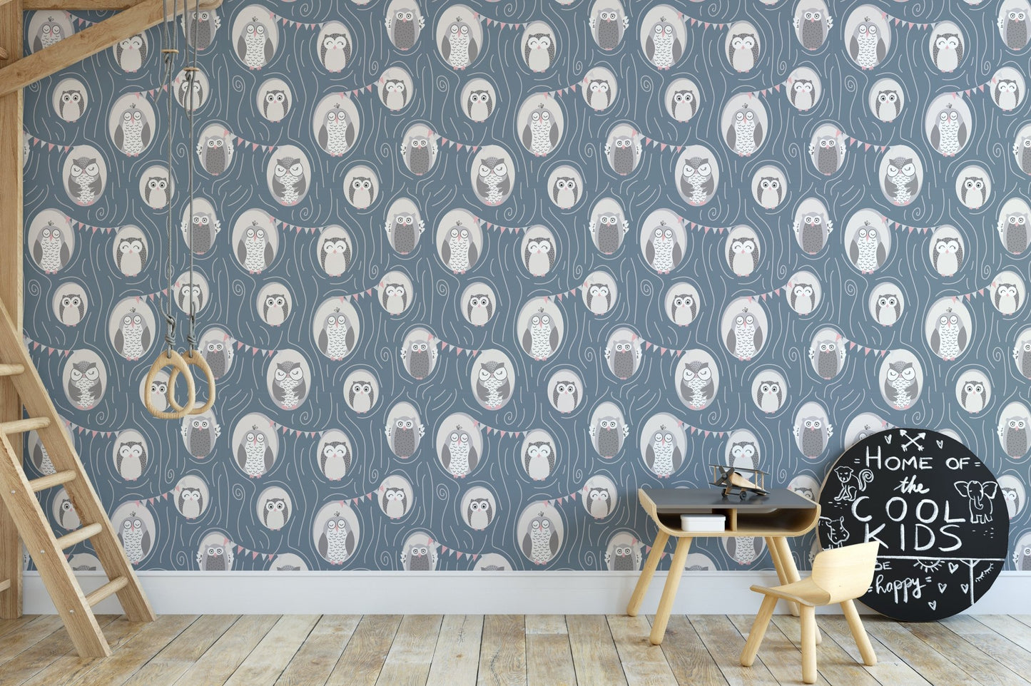 Kids' study space with blue owl wallpaper and wooden desk with chair.