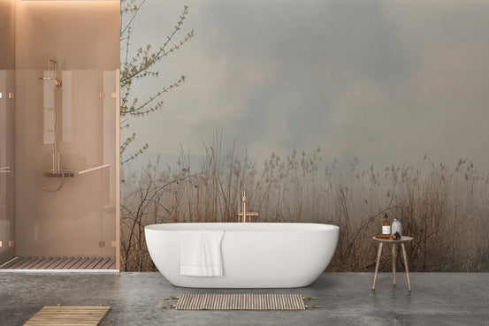 Modern bathroom with a white tub against a misty reed pattern wall mural.