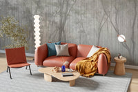 Whispers of the Woods Wall Mural behind a tan leather sofa and orange armchair.