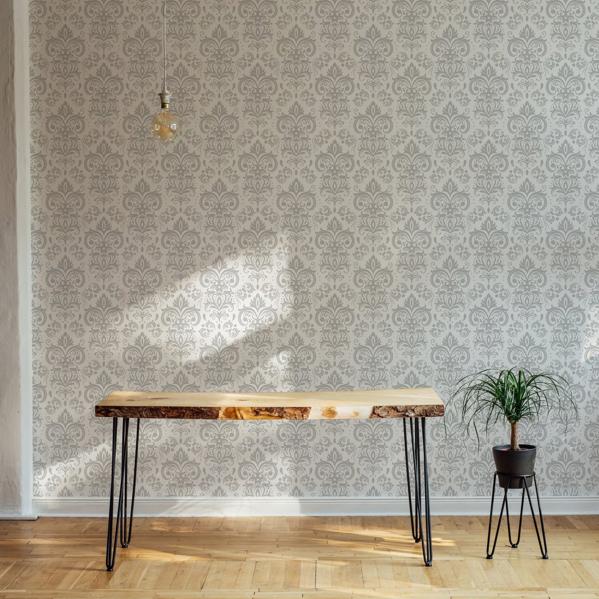 White and grey damask wall mural behind a wooden console table in a sunlit room.