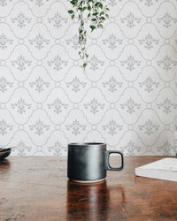 White and grey color vintage look damask wallpaper behind a wooden table and mug.