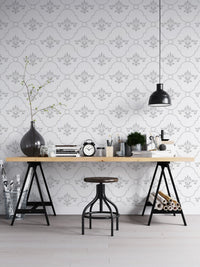 Damask style wallpaper in a workspace with a wooden desk and black industrial stool.