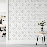 Vintage damask wallpaper behind a small side table and potted plant in a living area.