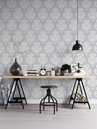 Damask pattern wallpaper behind a black industrial desk and metal stool.