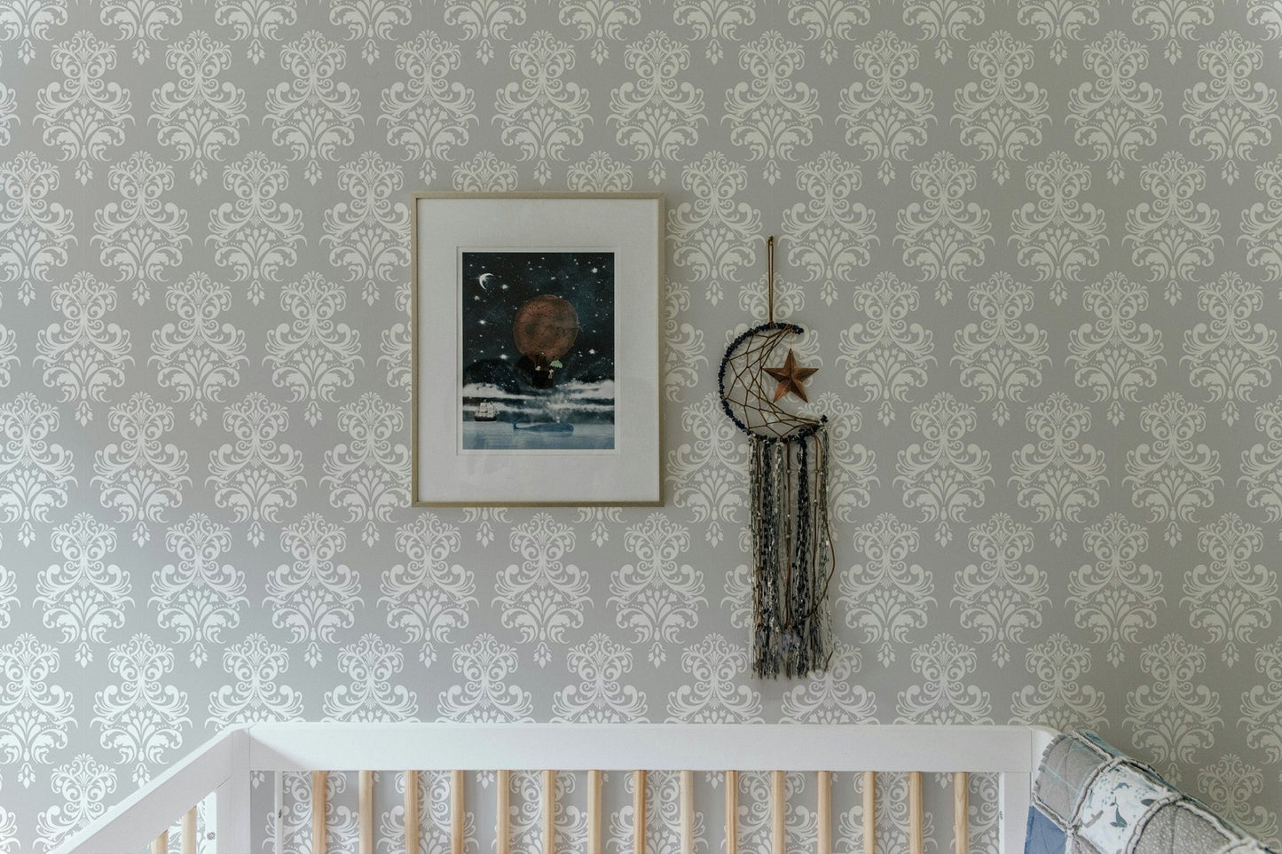 Grey and white damask wallpaper in a nursery with a white crib.