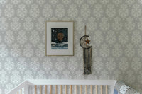 Grey and white damask wallpaper in a nursery with a white crib.