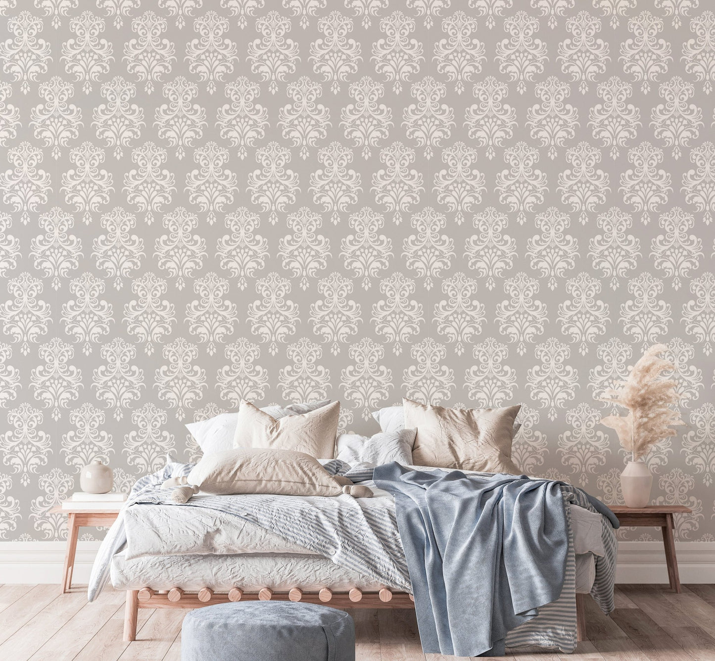 Grey damask wallpaper in a bedroom with a bed and blue throw blanket.