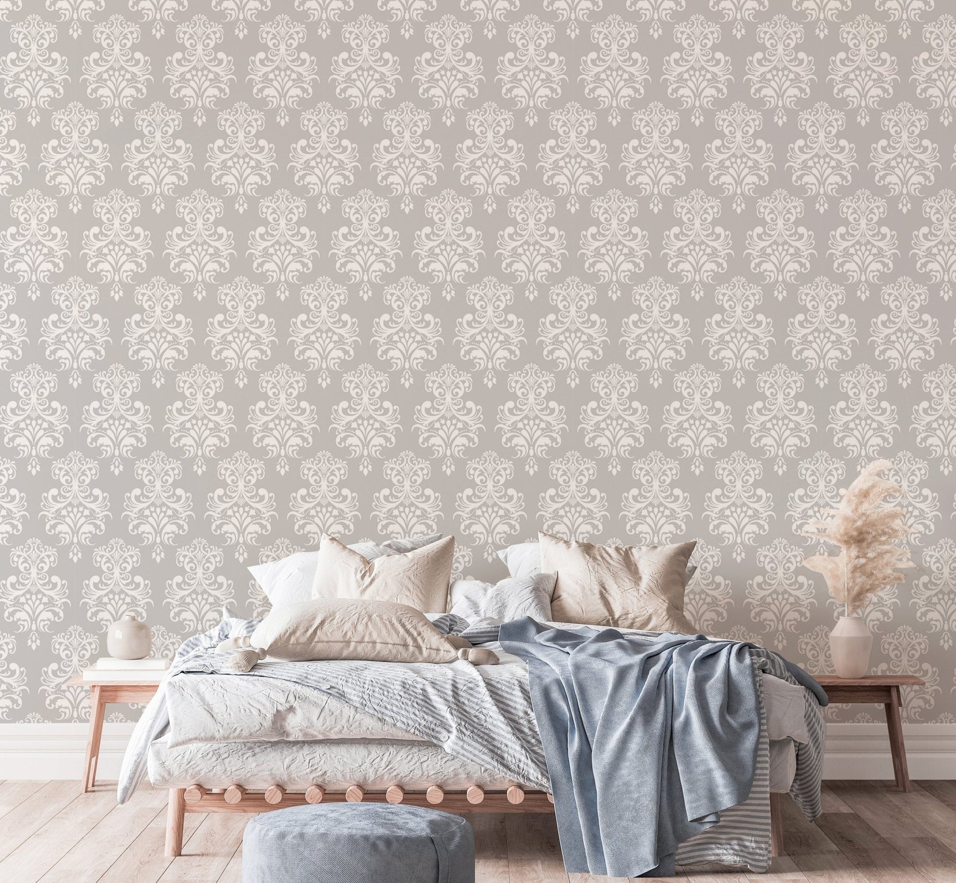Grey damask wallpaper in a bedroom with a bed and blue throw blanket.