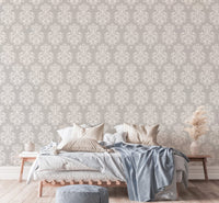 Grey damask wallpaper in a bedroom with a bed and blue throw blanket.