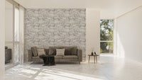 Large living space with a grey sofa and a white stone texture wallpaper.