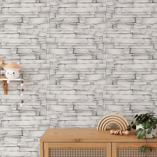 White color limestone masonry wallpaper behind a light wood sideboard with decor.