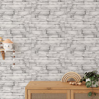 White color limestone masonry wallpaper behind a light wood sideboard with decor.