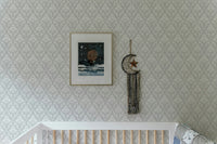 Neutral damask wallpaper in a nursery room above a white wooden crib.