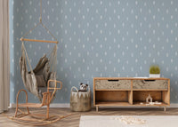 Pine tree wallpaper on feature wall with hanging chair and wooden console.