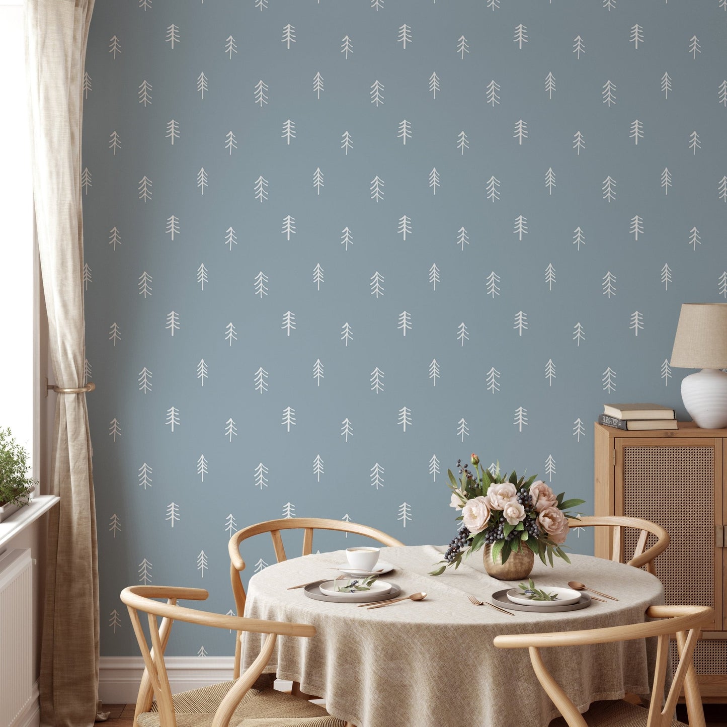 White pine tree wallpaper on blue wall in dining room with round table.