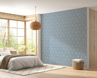 Blue and white tree wallpaper in spacious bedroom with wooden floors.