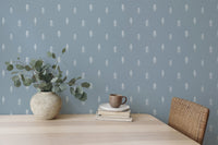 Minimalist tree pattern wallpaper behind wooden dining furniture and plant.