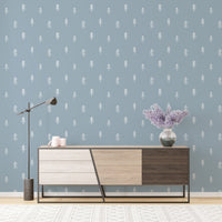 Minimalist tree wallpaper behind modern sideboard with lamp and purple flowers.