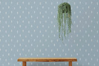 Blue wallpaper with white trees in living area with hanging green plant.