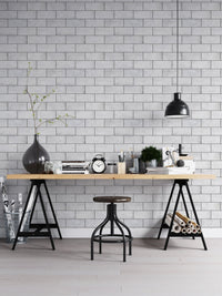 Desk with black lamp against a light grey brick wallpaper.